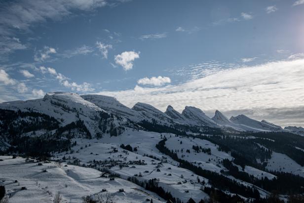 Winterliche Landschaft mit schneebedeckten Bergen und vereinzelten Häusern.