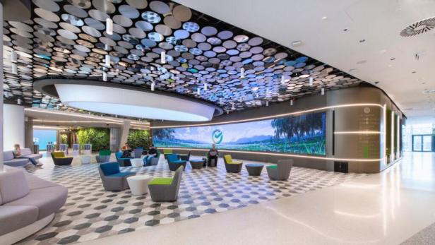 Eine moderne Bankhalle mit Sitzgelegenheiten und einem großen Bildschirm.