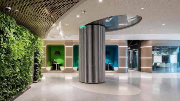 Ein modernes Büro mit einer grünen Wand und einzelnen Arbeitskabinen.