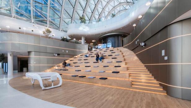 In einem modernen Gebäude sitzen Menschen auf einer breiten Treppe mit Sitzkissen.