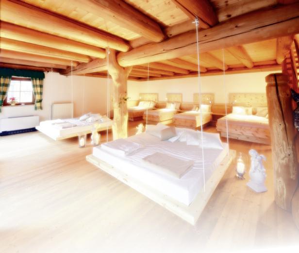 Ein Zimmer mit mehreren schwebenden Betten und Holzbalkendecke.