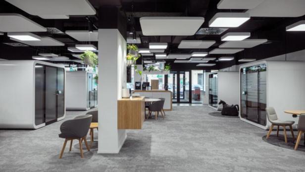 Ein modernes Büro mit weißen Telefonzellen und Besprechungsbereichen.