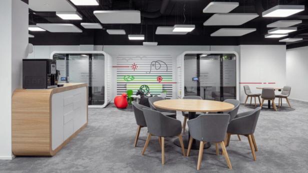 Ein moderner Büroraum mit Besprechungstisch, Stühlen und zwei Telefonzellen.