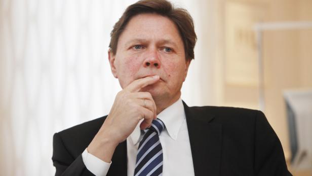 Ein Mann im Anzug mit Krawatte denkt nach, den Finger am Kinn.