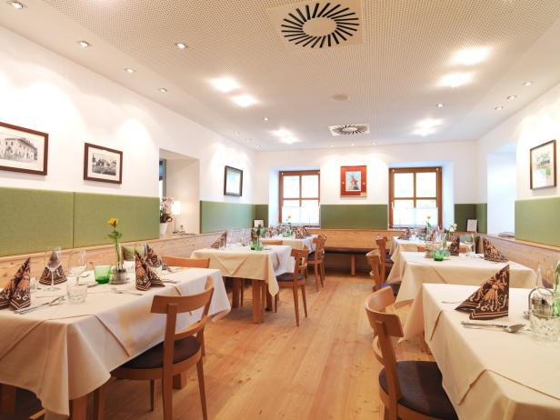 Ein helles Restaurant mit gedeckten Tischen und Holzboden.