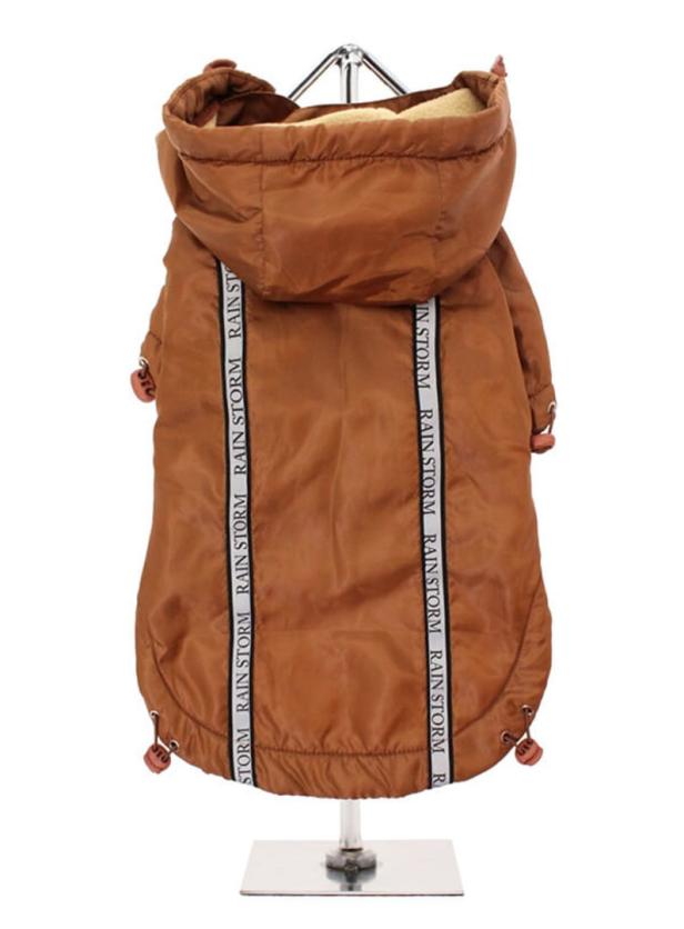 Eine braune Hundejacke mit Kapuze und dem Aufdruck „Rain Storm“ hängt an einem Kleiderbügel.