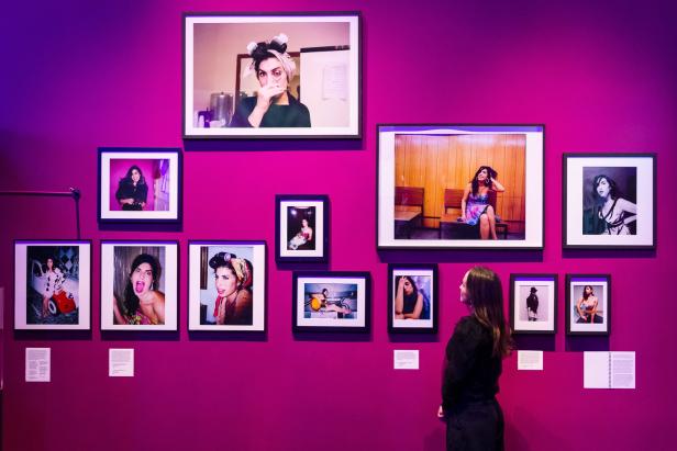 Eine Frau betrachtet eine Wand mit Fotografien von Amy Winehouse in einer Kunstgalerie.