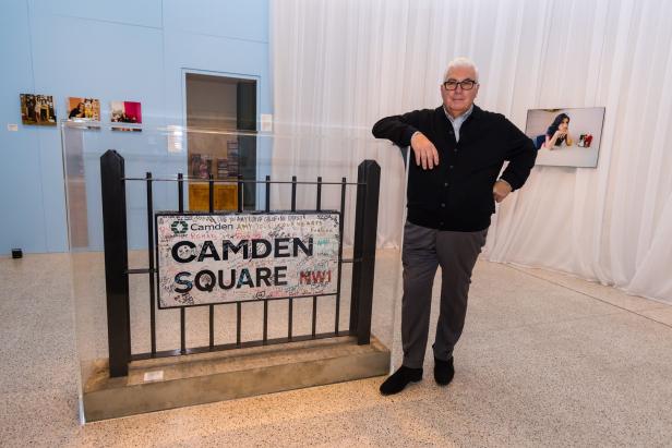 Ein Mann steht neben einem Schild mit der Aufschrift „Camden Square“ in einer Ausstellung.
