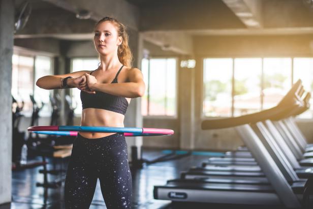 Eine Frau trainiert mit einem Hula-Hoop-Reifen in einem Fitnessstudio.