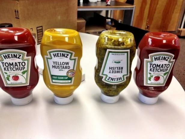 Vier Flaschen Heinz-Ketchup, Senf und Relish stehen auf einem Tisch.