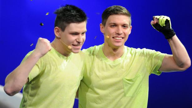 Zwei junge Männer in hellgrünen T-Shirts jubeln vor einem blauen Hintergrund.
