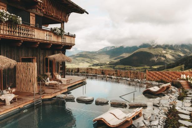 Ein luxuriöses Holzchalet mit Pool und Blick auf die Berge.