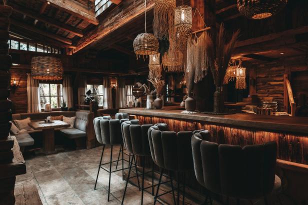 Eine Bar in einer Hütte mit Hockern und dekorativen Lampen.