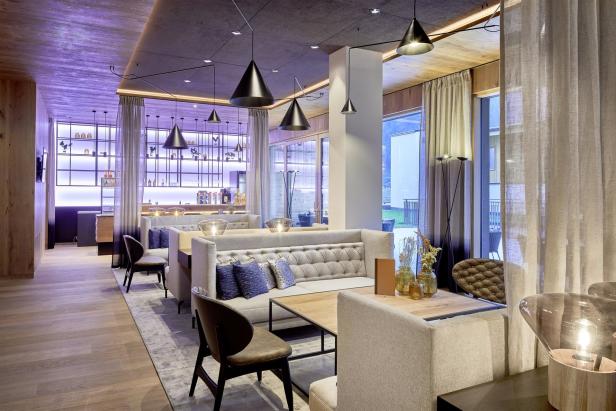 Ein modern eingerichteter Innenraum mit Sitzgelegenheiten und einer Bar im Hintergrund.