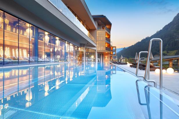 Ein Außenpool spiegelt die Architektur eines modernen Hotels in den Bergen wider.