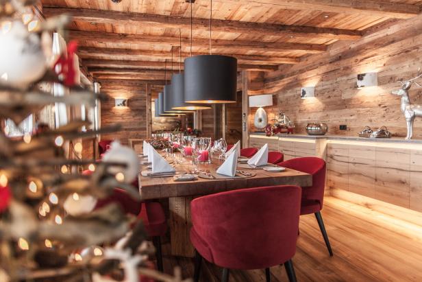 Ein festlich gedeckter Tisch in einem holzvertäfelten Raum mit roten Stühlen.