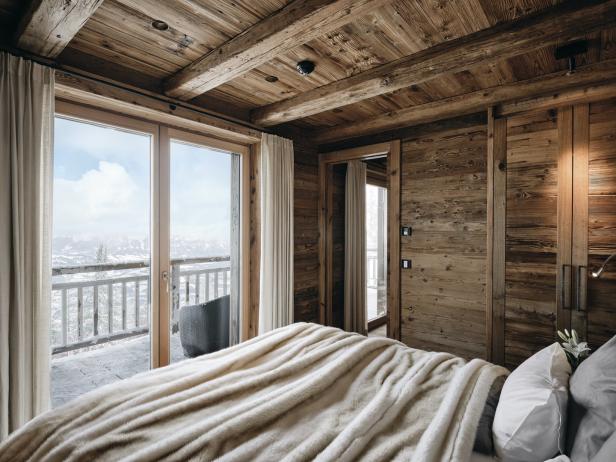 Ein Schlafzimmer mit Holzwänden und Blick auf schneebedeckte Berge.