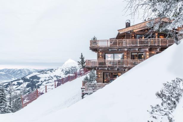 Ein luxuriöses Holzchalet liegt inmitten einer verschneiten Berglandschaft.