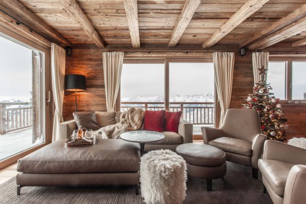 Ein gemütliches Wohnzimmer mit Holzwänden und Blick auf schneebedeckte Berge.