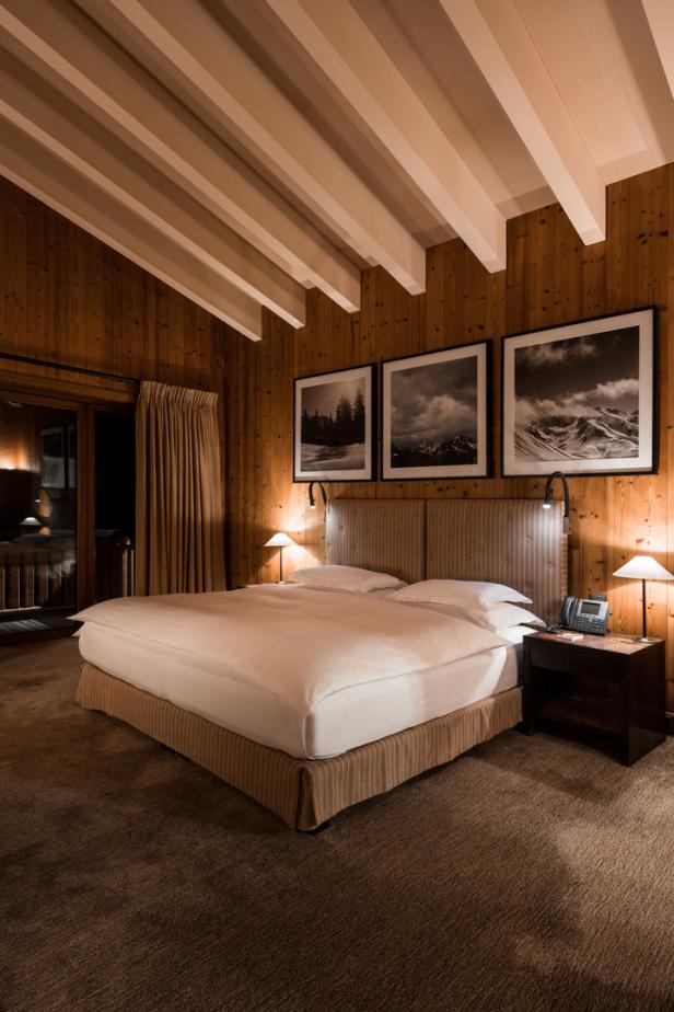 Ein Schlafzimmer mit Holzwänden und drei Landschaftsbildern über dem Bett.