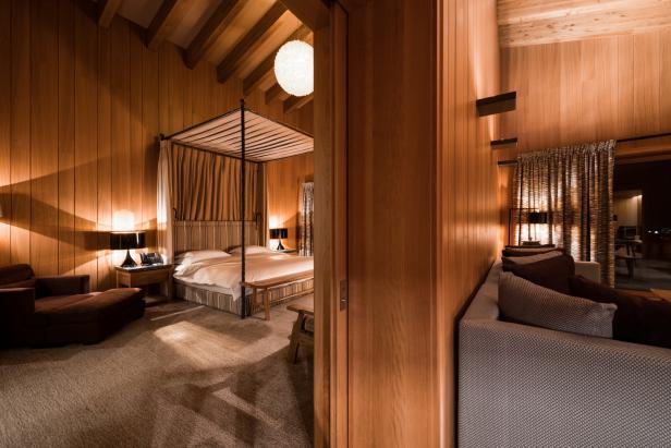 Ein Schlafzimmer mit Holzwänden und einem Himmelbett unter einer runden Lampe.