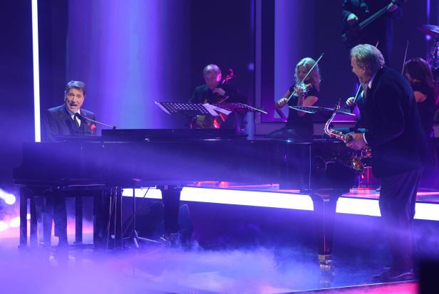 Ein Pianist spielt auf der Bühne, begleitet von einem Orchester.