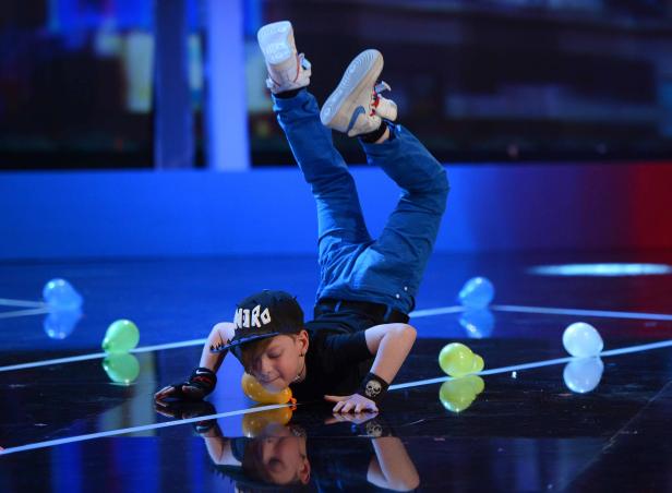 Ein junger Breakdancer macht einen Handstand auf einer Bühne mit Ballons.
