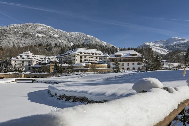 Ein verschneites Hotel in einer Winterlandschaft mit Bergen im Hintergrund.