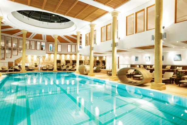 Ein Innenpool mit türkisfarbenem Wasser und Liegebereichen an den Seiten.