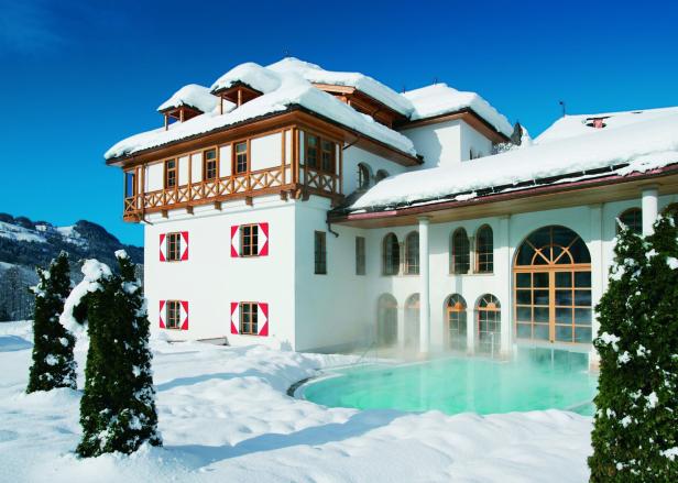 Ein schneebedecktes, weißes Gebäude mit einem Außenpool im Winter.
