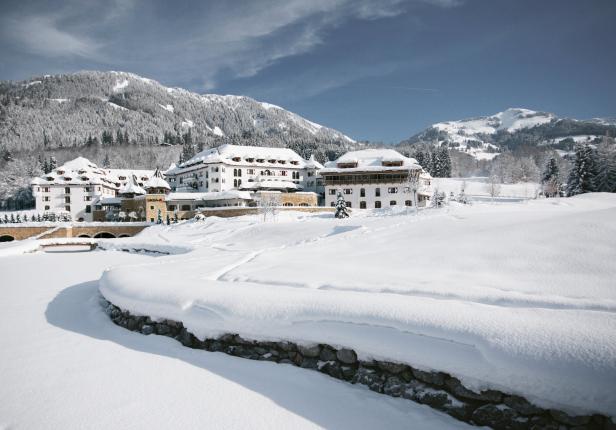 Ein verschneites Hotel liegt vor einer Bergkulisse.
