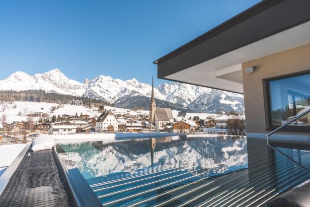 Ein Blick von einem Pool auf ein verschneites Dorf in den Alpen.