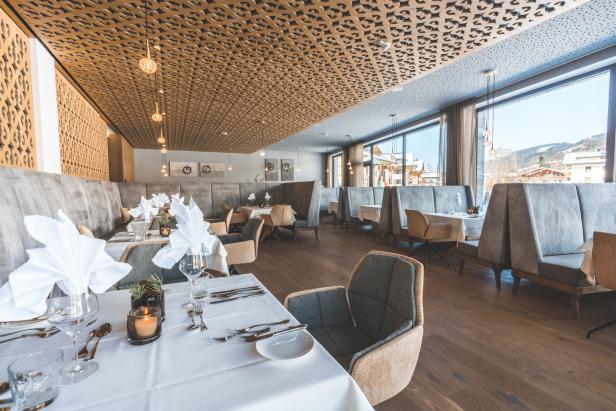 Ein elegant gedeckter Tisch in einem hellen Restaurant mit großen Fenstern und Blick auf die Berge.