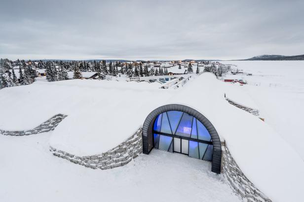 Ein schneebedecktes Gebäude mit einem gewölbten Eingang in einer Winterlandschaft.