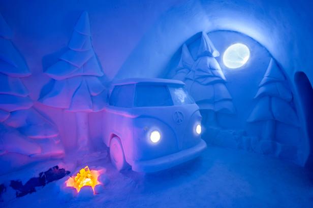 Ein VW-Bus aus Eis steht in einer Höhle mit Eisbäumen und einem Lagerfeuer.