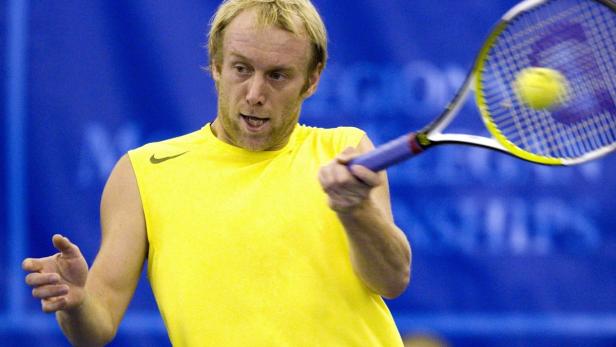 Ein Tennisspieler schlägt einen Ball mit seinem Schläger.