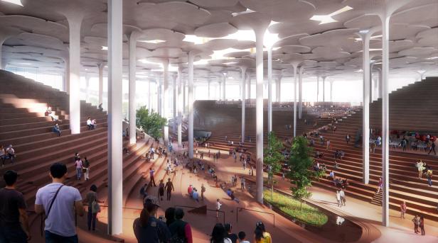 Menschen sitzen und gehen in einer großen Halle mit stützenden Säulen und Treppen.