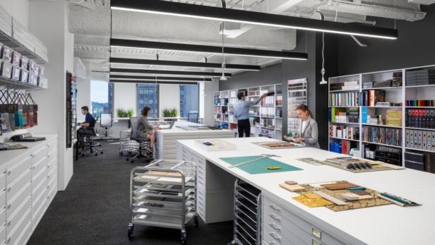 In einem Büro arbeiten mehrere Personen an großen Tischen mit Materialproben.