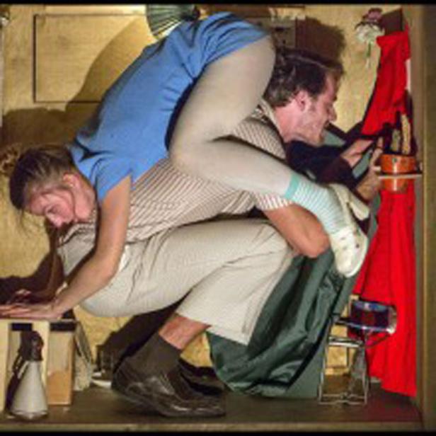 Ein Mann und eine Frau zwängen sich in einen kleinen Schrank.