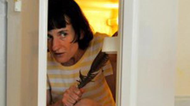 Eine Frau schaut durch eine Tür und hält eine Feder in der Hand.