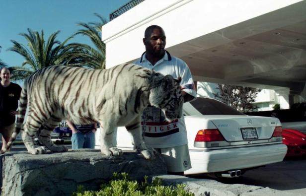 Mike Tyson steht mit einem weißen Tiger vor einem weißen Mercedes.