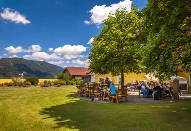Gäste sitzen im Biergarten eines Gasthofs in ländlicher Umgebung.