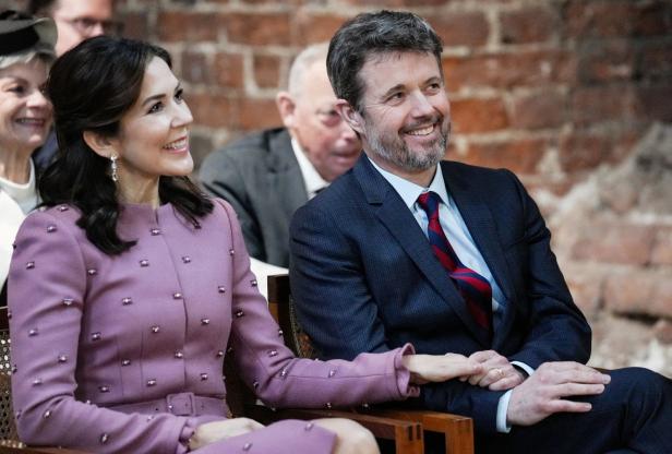 Kronprinzessin Mary und Kronprinz Frederik sitzen lächelnd nebeneinander.