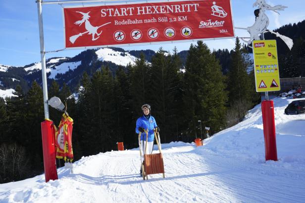 Eine Frau steht mit einem Schlitten am Startpunkt des „Hexenritt“ in Söll.