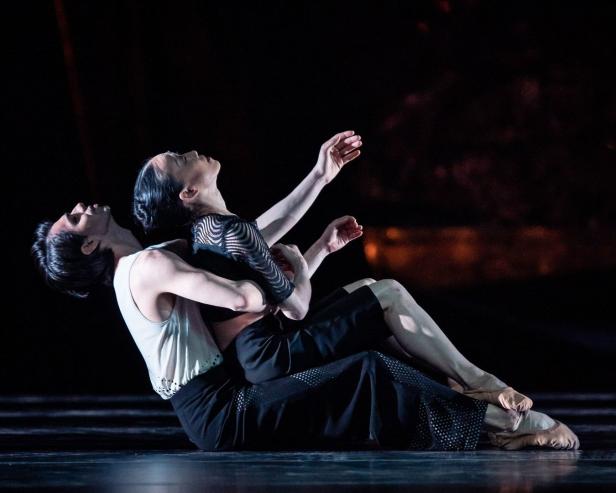 Zwei Balletttänzer liegen auf der Bühne und führen eine anmutige Bewegung aus.