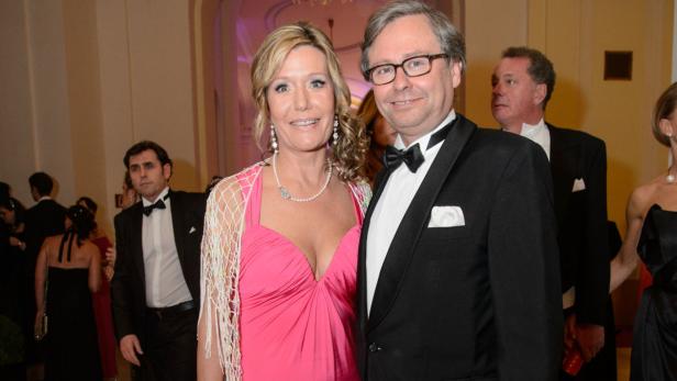 Eine Frau in einem pinkfarbenen Kleid und ein Mann im Smoking posieren für ein Foto auf einem Ball.