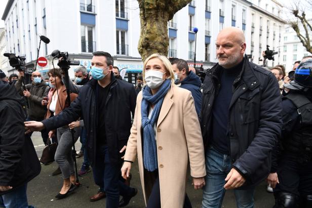 Marine Le Pen mit Anhängern und Sicherheitskräften auf einer Straße.