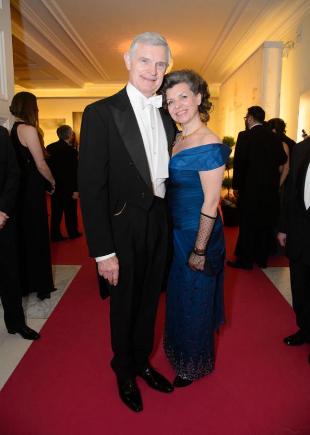 Ein Mann im Smoking und eine Frau im blauen Abendkleid posieren auf einem roten Teppich.