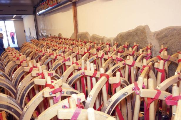 Viele Holzschlitten mit roten Bändern stehen in einem Raum.