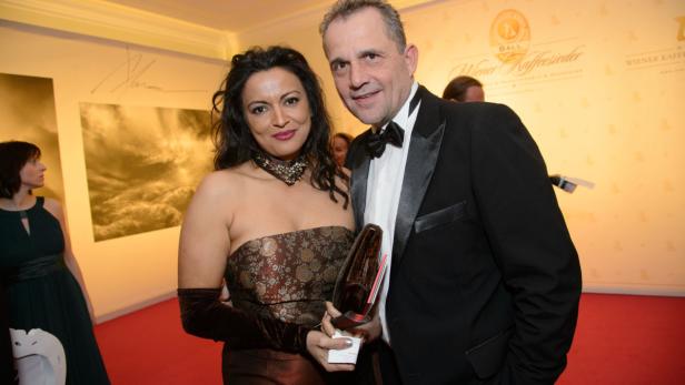 Eine Frau im Abendkleid und ein Mann im Smoking posieren für ein Foto.